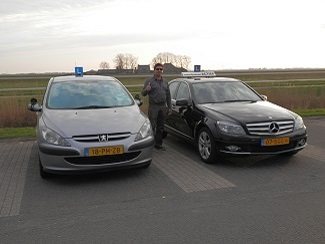 De rijinstructeur van Autorijschool Actief tussen de Peugeot en de Mercedes lesauto