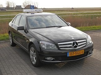De Mercedes C220 CDI lesauto van Autorijschool Actief, driekwart vooraanzicht met het L-bord op het dak
